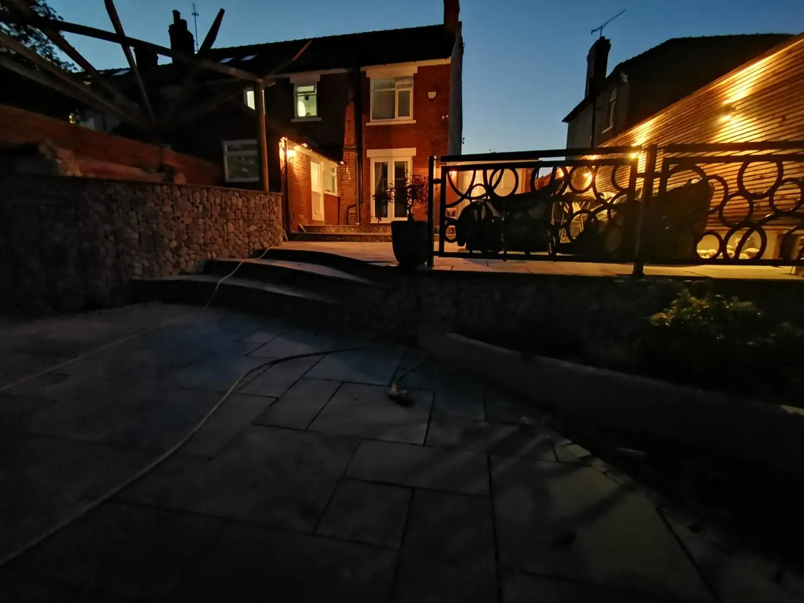 Rear garden with slate patio, gabion walls, and timber screening