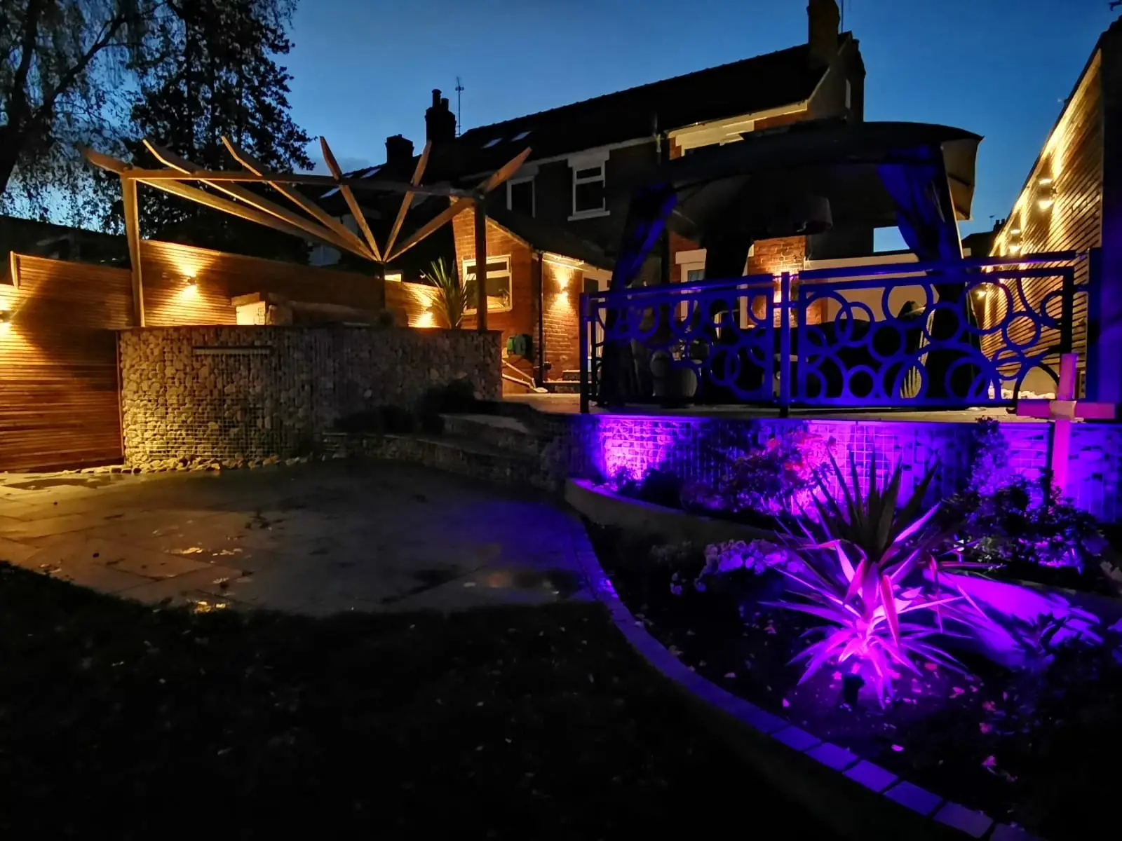 Rear garden with slate patio, gabion walls, and timber screening
