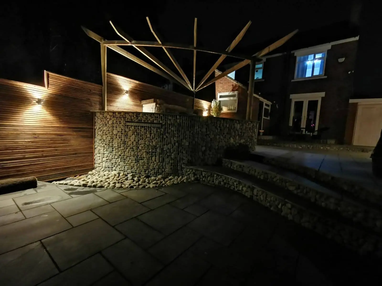 Rear garden with slate patio, gabion walls, and timber screening