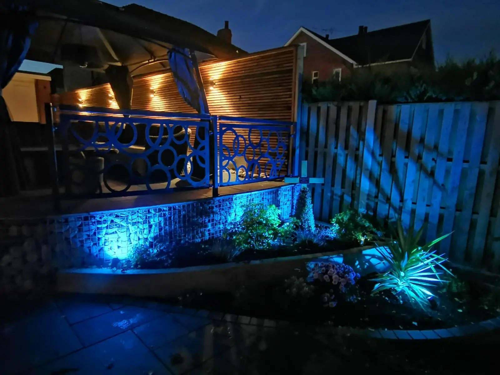 Rear garden with slate patio, gabion walls, and timber screening