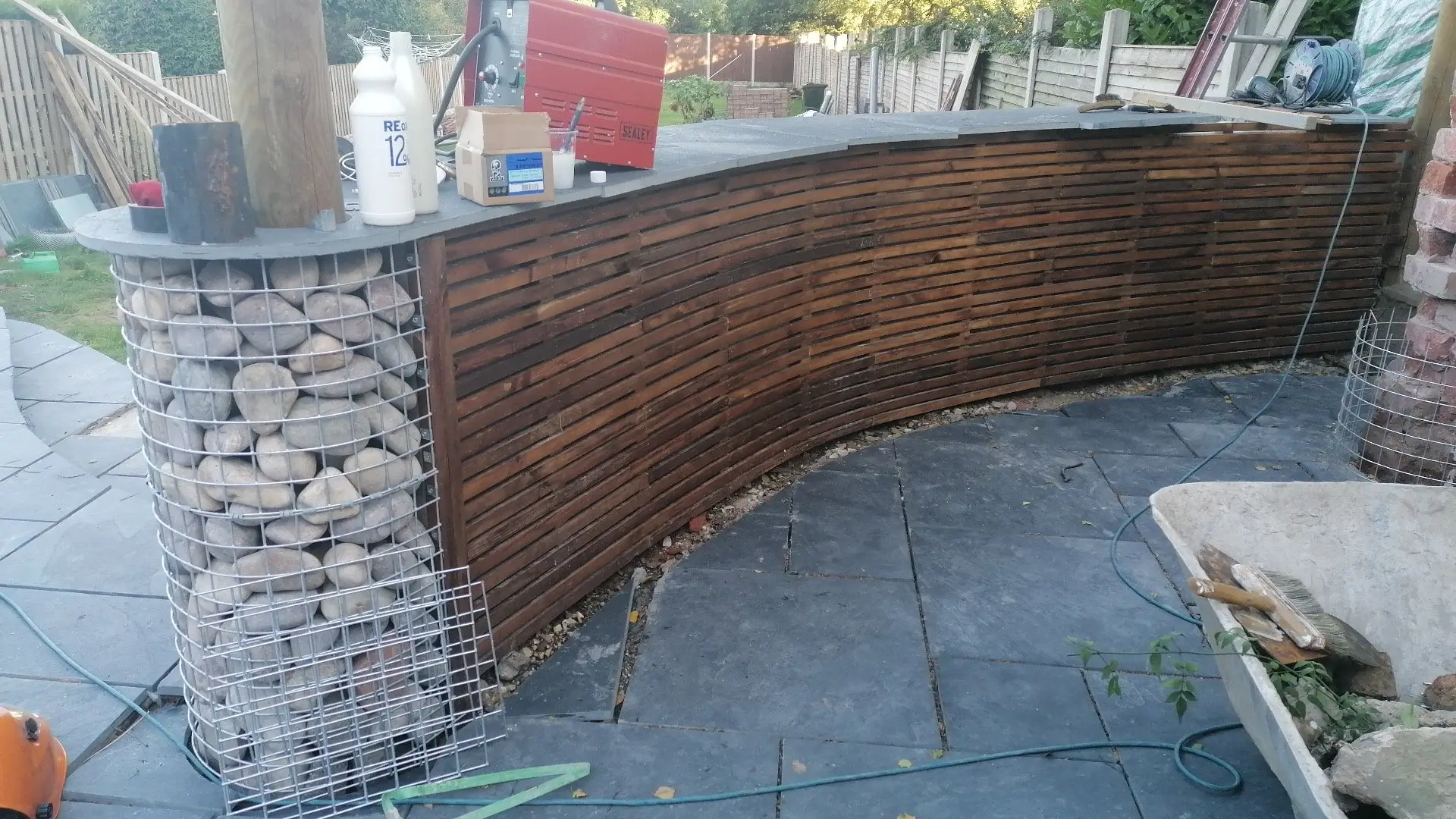 Rear garden with slate patio, gabion walls, and timber screening