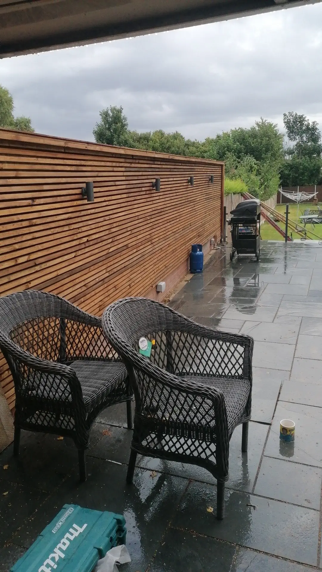 Rear garden with slate patio, gabion walls, and timber screening